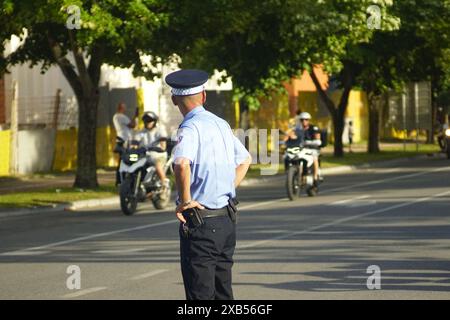 Ein Polizist hält Ordnung beim 24. Motorradtreffen. Ein Streifenpolizist, der auf der Straße steht, beobachtet Motorradfahrer, die an einer Stadtstraße vorbeifahren. Stockfoto