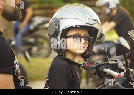 Trebinje, Bosnien und Herzegowina - 08.06.2024: 24. Motorradtreffen. Porträt eines Jungen in einem Schutzhelm, der auf einem Motorrad sitzt. Stockfoto