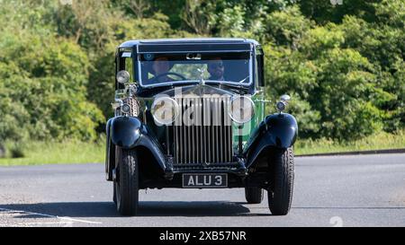 Stony Stratford, UK - 2. Juni 2024: 1933 grüner Rolls Royce Oldtimer fährt auf einer britischen Landstraße Stockfoto