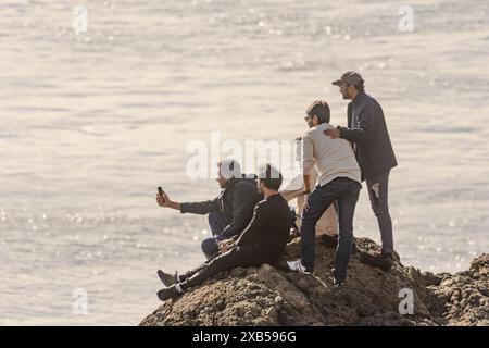 Eine Sightseeing-Gruppe macht ein Selfie auf einem Felsen mit Blick auf das Wasser in der Nähe von Anchorage, Alaska Stockfoto