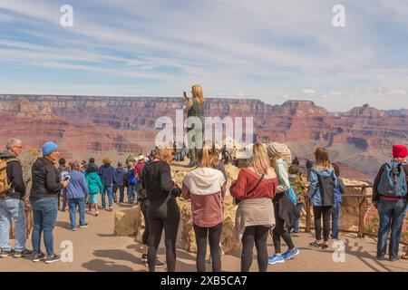 Lady steht auf einem großen Felsen und macht ein Foto vom Grand Canyon in Arizona mit ihrem Handy. Stockfoto