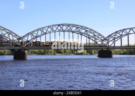 Die Eisenbahnbrücke, die den Fluss Daugava in Riga überquert, ist die erste Eisenbrücke, die 1871–1872 errichtet wurde. Stockfoto