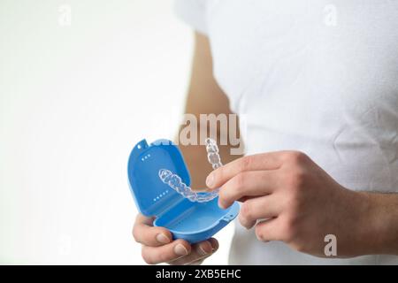 Nahaufnahme eines jungen Mannes mit unsichtbarem Zahnhalteapparat und einem Koffer zu ihrer Aufbewahrung und zum Schutz. Männliche Hände, die Zahnaligner halten Stockfoto