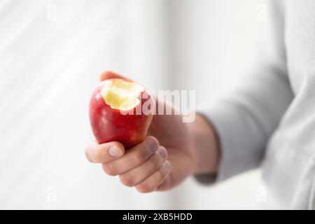 Männliche Hand hält gebissenen Apfel Kopierraum, Mann isst einen Apfel Nahaufnahme selektiven Fokus Stockfoto
