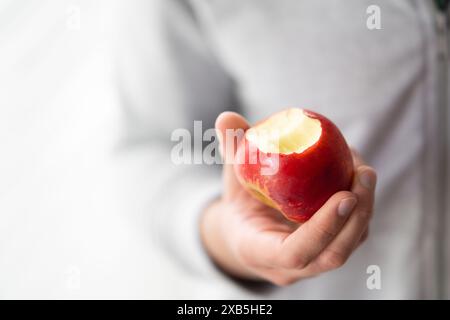 Männliche Hand hält gebissenen Apfel Kopierraum, Mann isst einen Apfel Nahaufnahme selektiven Fokus Stockfoto