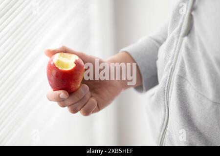 Männliche Hand hält gebissenen Apfel Kopierraum, Mann isst einen Apfel Nahaufnahme selektiven Fokus Stockfoto