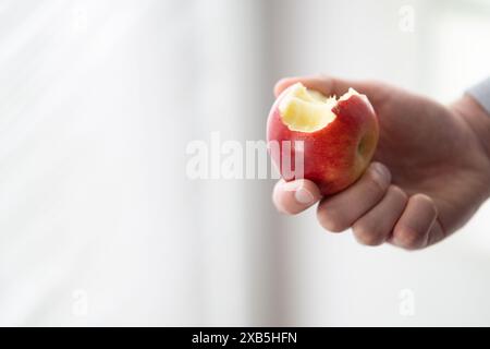 Männliche Hand hält gebissenen Apfel Kopierraum, Mann isst einen Apfel Nahaufnahme selektiven Fokus Stockfoto