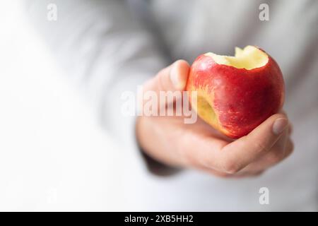 Männliche Hand hält gebissenen Apfel Kopierraum, Mann isst einen Apfel Nahaufnahme selektiven Fokus Stockfoto