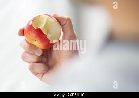 Männliche Hand hält gebissenen Apfel Kopierraum, Mann isst einen Apfel Nahaufnahme selektiven Fokus Stockfoto