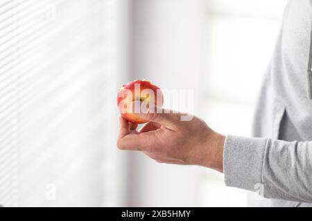 Männliche Hand hält gebissenen Apfel Kopierraum, Mann isst einen Apfel Nahaufnahme selektiven Fokus Stockfoto