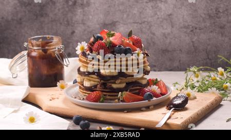 Pfannkuchen mit Banane, Heidelbeeren, Erdbeeren und Schokoladensauce auf einem Teller. Stockfoto