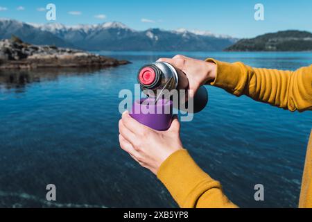 Beschnittene Hände machen Yerba Mate Tea in Cup, nahe dem See. Stockfoto