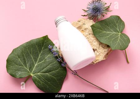 Zusammensetzung mit Flasche Kosmetik, Blumen und Efeublättern auf farbigem Hintergrund Stockfoto