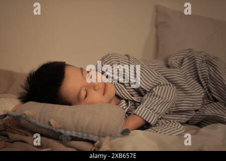 Süßer kleiner asiatischer Junge im Pyjama, der im Bett schläft Stockfoto