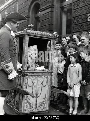 13. Mai 1953: London, England, Vereinigtes Königreich: Im Rahmen der Bath Assembly Feiern findet eine Mode vom 18. Bis 20. Jahrhundert durch die Straßen der Stadt Bath statt. die Kleider wurden von den Familienangehörigen gesammelt und die Kosten von Familien, die in der Gegend um Bath und Westengland leben. Die Damen aus der modischen Vergangenheit der Stadt kamen im Octagon in den Sedanstühlen an. MRE. F.R. JARMAN macht ein charmantes Studium, als sie in einem Sedanstuhl im Octagon ankam. Kreditbild: © Keystone Press Agency/ZUMA Press Wire). REDAKTIONELLE VERWENDUNG O Stockfoto