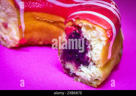 Nahaufnahme von einem Donut mit Marmelade drin, auf einem lila Hintergrund. Stockfoto