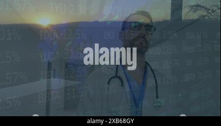Bild eines kaukasischen Mannes mittleren Alters, der Brille und Stethoskop trägt und auf einen Bildschirm mit Daten blickt Stockfoto