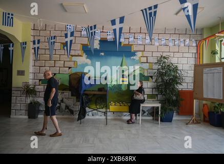 Athen, Griechenland. Juni 2024. Die Wähler stehen neben einer Wahlkabine in einem Wahllokal, das mit griechischen Fahnen verziert ist. Die Wähler in 27 Ländern der Europäischen Union gehen zwischen dem 6. Und 9. Juni zur Wahl der Mitglieder des Europäischen Parlaments. (Foto von Dimitris Aspiotis/Pacific Press) Credit: Pacific Press Media Production Corp./Alamy Live News Stockfoto