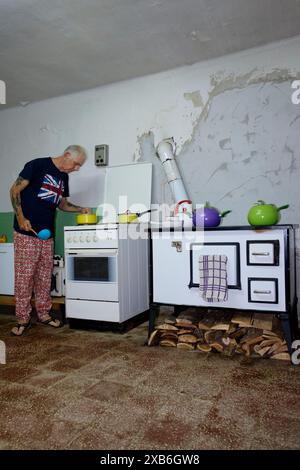 Reife männliche britische Expat in angemessener Kleidung kochen Essen in seiner Küche für andere Expats zala County ungarn Stockfoto