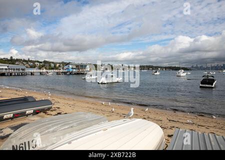 Watsons Bay Beach mit Ruderbootladen am Ufer und Blick über den Hafen zum Stadtzentrum von Sydney und CBD mit Hochhäusern, NSW, Australien Stockfoto