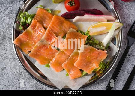 Räucherlachs mit Gemüse darunter auf einem Steintisch Stockfoto