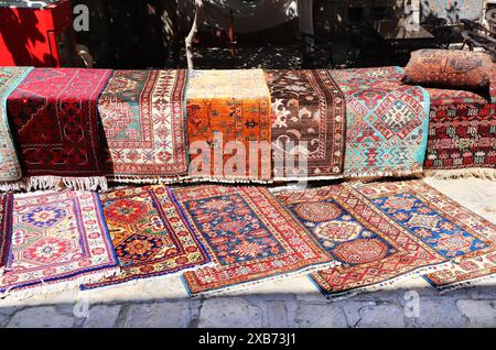 Bunte kleine Teppiche auf einem Straßenbasar in der Altstadt von Samarkand, Usbekistan. Traditioneller usbekischer Teppich zum Souvenir-Shopping Stockfoto