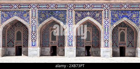 Berühmtes Wahrzeichen - Sher-Dor Madrasah auf dem Registan-Platz, Samarkand, Usbekistan. Bögen mit Fliesenverzierungen im Innenhof von Sher Dor Madrasa Stockfoto