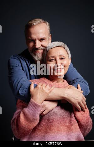 Porträt eines lächelnden Seniorenpaares, das im Studio die Kamera umschließt und ansieht Stockfoto