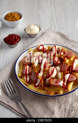 Hausgemachte Salchipapa-Pommes mit Ketchup, Senf und Mayo auf einem Teller, Seitenansicht. Stockfoto