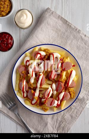 Hausgemachte Salchipapa-Pommes mit Ketchup, Senf und Mayo auf einem Teller, Blick von oben. Stockfoto