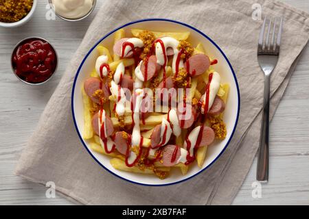 Hausgemachte Salchipapa-Pommes mit Ketchup, Senf und Mayo auf einem Teller, Blick von oben. Stockfoto