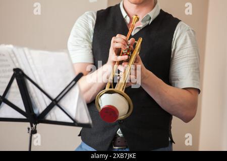 Die Trompete mit gerader Stummschaltung ist in den Händen der Trompeter. Nahaufnahme mit selektivem Fokus. Hintergrundfoto mit Live-Musik Stockfoto