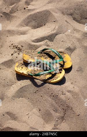 Eine Nahaufnahme von Havaianas Flipflops, die im Sand am Strand liegen Stockfoto