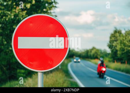 Verkehrsschild „No Entry“ an der europäischen Straße mit Auto- und Motorradfahren entlang der Autobahn, selektiver Fokus Stockfoto