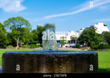 Nahaufnahme eines kleinen Springbrunnens in einem Stadtpark. Gefrorene Wasserströme gegen den blauen Himmel. Stockfoto