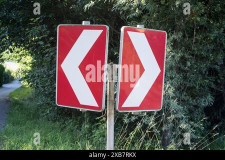 Eine Aufnahme von zwei roten und weißen Richtungsschildern mit Pfeilen in entgegengesetzte Richtungen Stockfoto