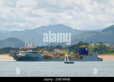 Eine Yacht, die an dem Hopper-Bagger-Schiff Tristao da Cunha vorbeifährt und in der Bucht Santander Cantabria in Spanien arbeitet Stockfoto