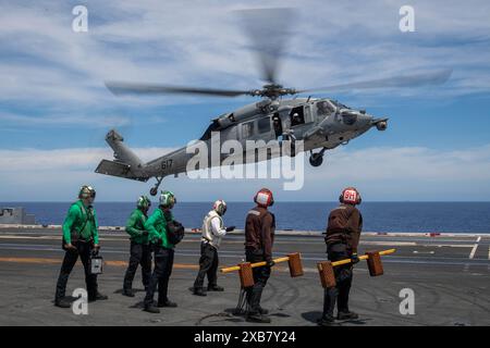 240610-N-BE723-1065 PHILIPPINISCHE SEE (10. Juni 2024) Seeleute stehen als MH-60S Sea Hawk zur Seite, die an den Golden Falcons of Helicopter Sea befestigt sind Stockfoto