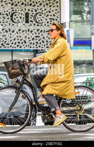 Junge Frau, die ein klassisches Fahrrad mit dem „Arcade Charleston“ entlang der Straße im Stadtzentrum fährt - Tours, Indre-et-Loire (37), Frankreich. Stockfoto