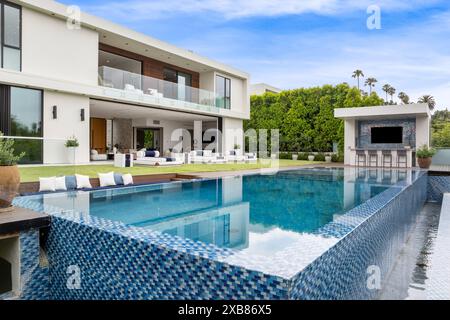 Ein geräumiger Pool neben einem zweistöckigen Haus mit Terrasse und Hof Stockfoto