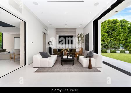 Ein möbliertes Wohnzimmer neben einer Glastür mit Blick auf einen grünen Außenbereich Stockfoto