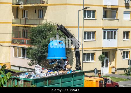 Sibiu City, Rumänien - 27. Mai 2024. Arbeiter keimen Container mit selektivem Müll in den Anhänger, Straßenreinigung, Männer laden Abfall aus Mülltonnen Stockfoto