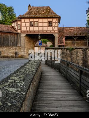 Eine hölzerne Brücke, die zu Stein- und Ziegelbauten über dem Wasser führt Stockfoto