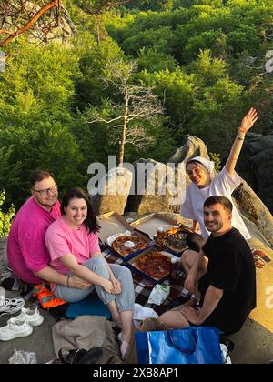 Glückliche Freunde, die Pizza auf der Bergklippe essen Stockfoto