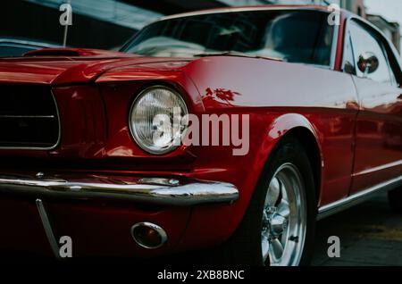 Roter Vintage Mustang parkte neben einem anderen Fahrzeug in der Stadt Stockfoto