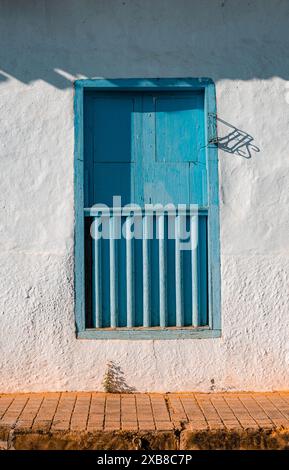 Weiße Stuckwand mit blauem Fenster und Holztür Stockfoto