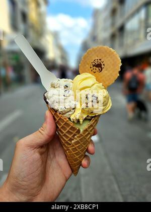 Eine Hand, die eine Eiskegel mit zwei Kugeln Eis hält Stockfoto