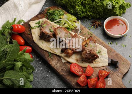Ein frisch gegrilltes Steak mit verschiedenen Gemüsesorten auf einem hölzernen Schneidebrett Stockfoto