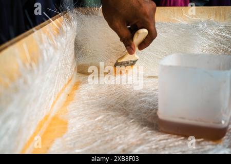 Bürstlösung durch Glasfaserplatten auf einer Holzkiste. Ein heimwerkerprojekt zu Hause. Stockfoto