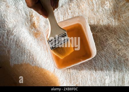 Pinsel in der Glasfaserlösung in einem Behälter auf der Glasfaserplatte. Stockfoto
